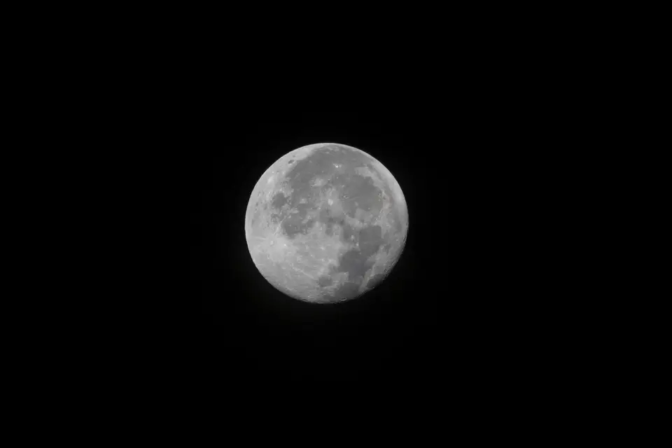 A bright full Moon rising in a dark sky.