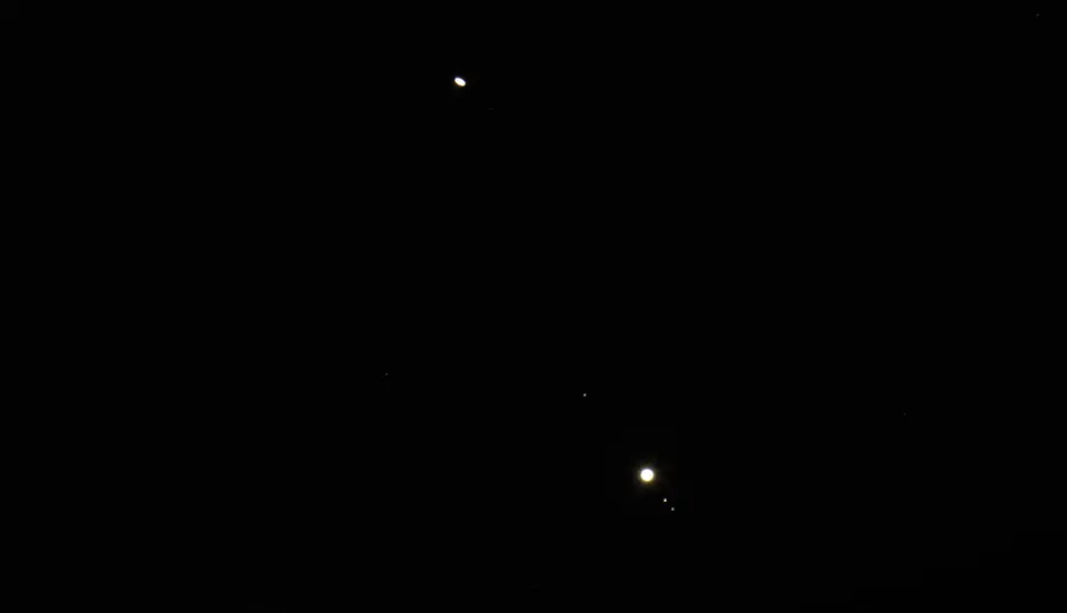 Two bright dots in a black sky, the lower one with tiny dots beside it.
