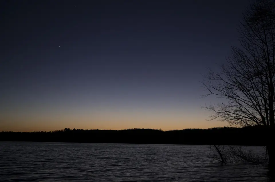 Two bright points close together in a twilight sky above a lake.